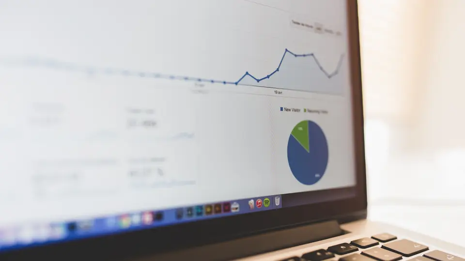 A laptop screen showing an analytics dashboard with a line graph of visits and a pie chart.